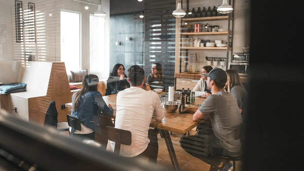 Três pessoas reunidas em volta de uma mesa de escritório, olhando um notebook e anotando em papel durante uma conversa de trabalho